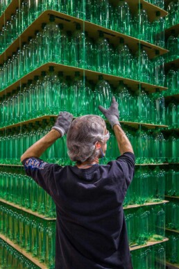 Commercial photo of production facility worker stacking green 2 liter bottles at Origlio Beverage in Philadelphia, PA.