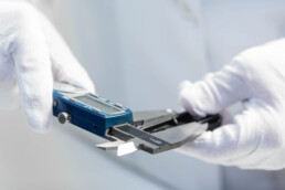Technician in white lab coat taking measurement with electronic caliper photographed on location by Tampa commercial photographer Carver Mostardi.